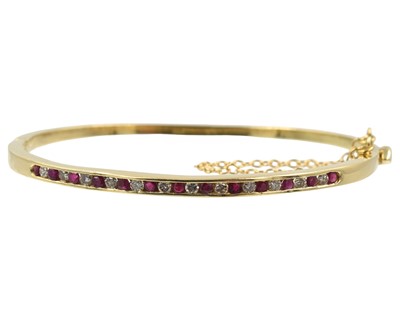 Lot 71 - An 18ct yellow gold, ruby and diamond hinged bangle