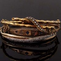 Lot 382 - Three gold hinged bangles set variously with seed